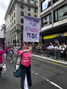 Gina Gwenffrewi stands in front of a march holding a placard with the slogan 'Marching for Istanbul Pride'